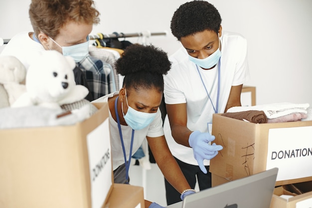 Guy and girl with check boxes Volunteers in masks with laptop Boxes with humanitarian aid