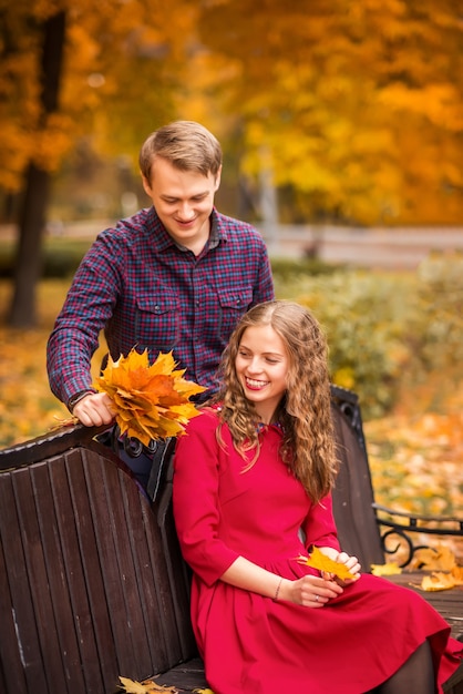 Guy gives a bouquet of autumn leaves to a girl .