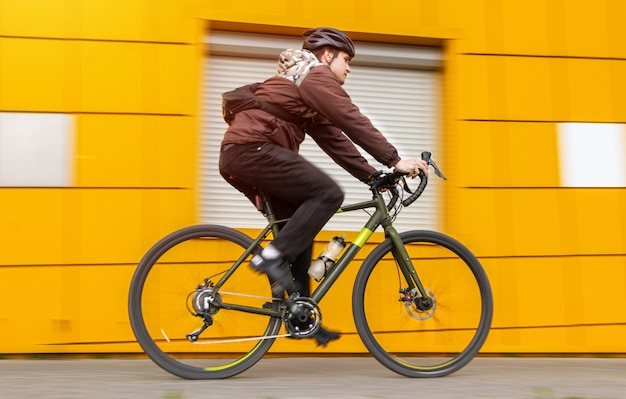 A guy on a gravel bike rides past a yellow wall