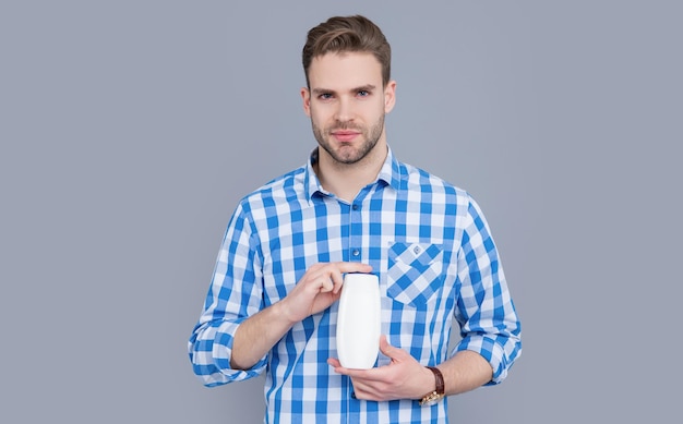 Guy hold aftershave product isolated on grey background guy with aftershave product