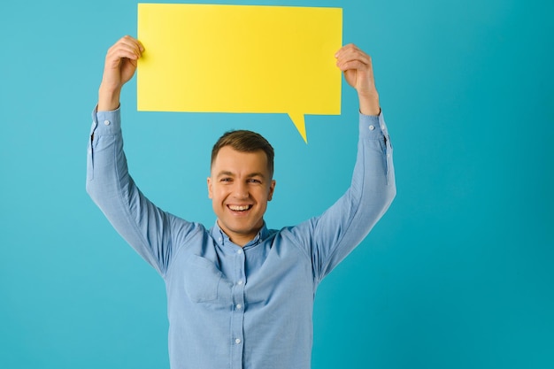 Guy holding speech bubble on blue studio background, mockup for design