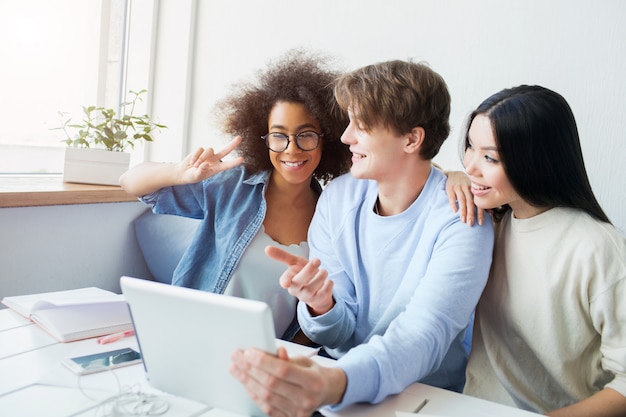 guy holding a tablet and girls talking with somebody using  tablet