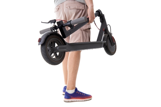 The guy holds a folded electric scooter on a white background