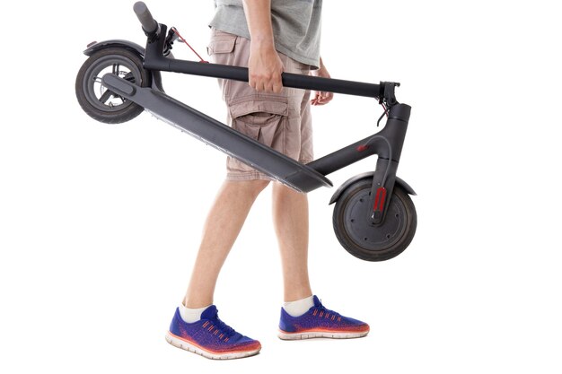 The guy holds a folded electric scooter on a white background