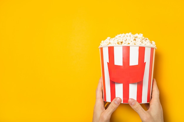 Il ragazzo tiene popcorn tra le mani su un muro giallo. posto per il testo.