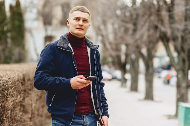 Guy in jas eenvoudige stands met telefoon