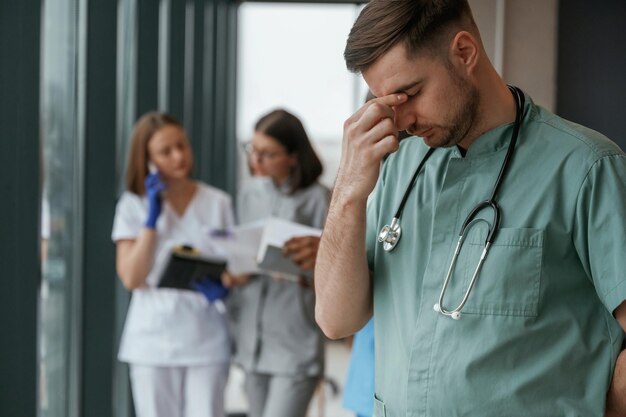 Guy is feeling bad Group of doctors are together indoors