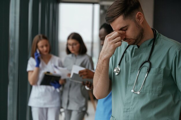 Guy is feeling bad Group of doctors are together indoors