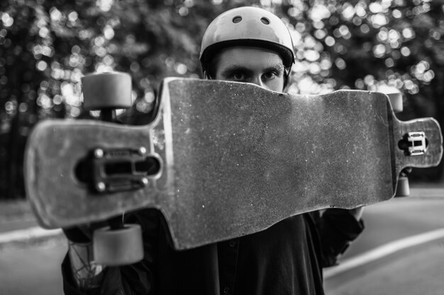 The guy is holding a longboard. Black and white portrait of an athlete. High quality photo