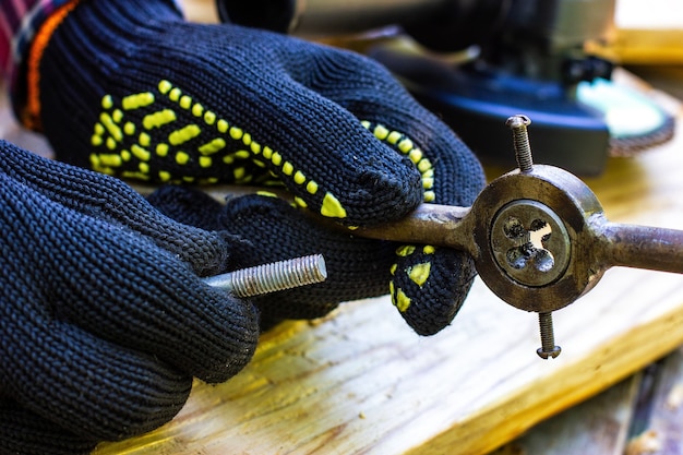 The guy is holding a tap for threading bolts locksmiths workshop