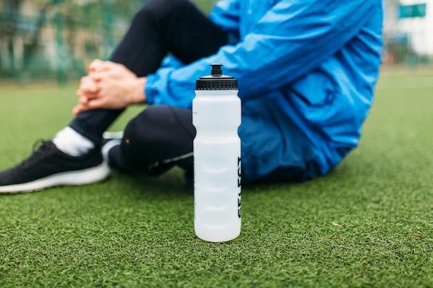 The guy is resting after a good workout. Guy after exercise, drinking water on the football field. Portrait of beautiful Guy in sportswear.