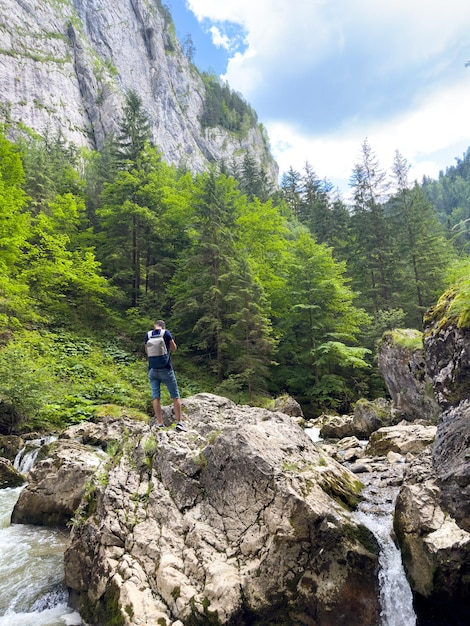 A guy is standing on large blocks of stone on a mountain river