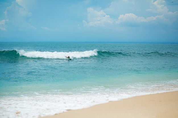 The guy is swimming on the surf board on the ocean. Healthy active lifestyle in summer vocation.