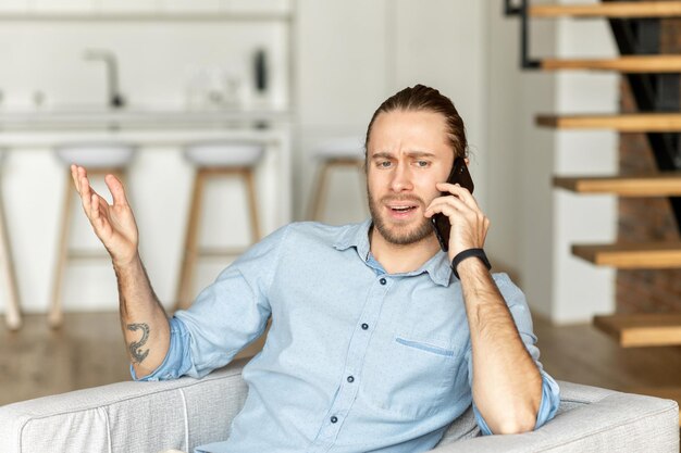 A guy is using smartphone sitting on the couch