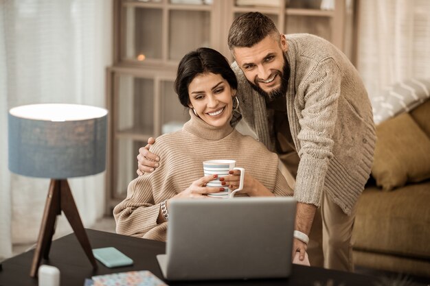 Guy knuffelen vrouw. Vreedzaam knap stel dat samen tijd doorbrengt in de kast terwijl ze inhoud op internet observeren