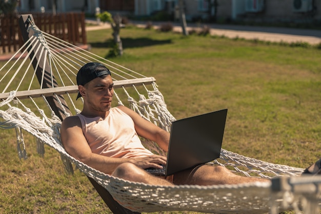 Guy ligt in een hangmat met een laptop