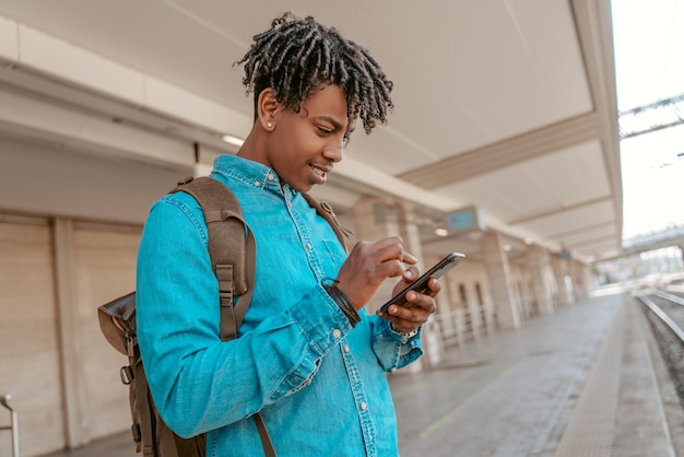Guy looking at smartphone waiting for arrival of train