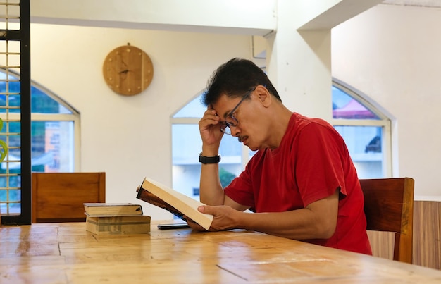 Photo guy looking tired of sitting and reading alone in the dining room