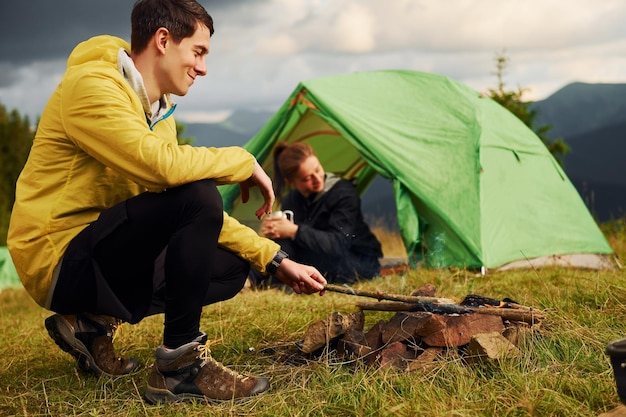 Guy making campfire Girlfriend just woke up Majestic Carpathian Mountains Beautiful landscape of untouched nature