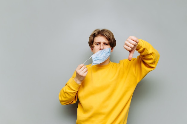 Guy in the medical mask shows a dislike gesture