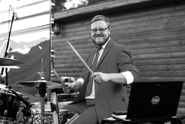 Guy musician plays the drum at a concert in stage lighting