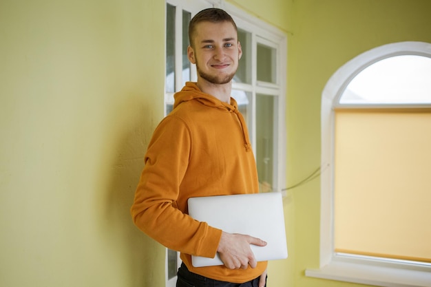 The guy in orange clothes holds a laptop in his hands