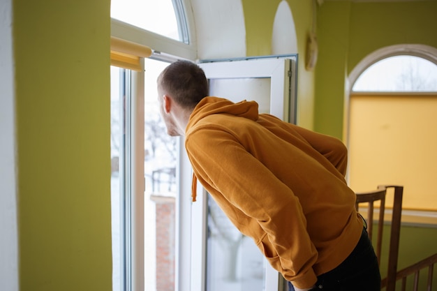 The guy in orange clothes opens the window and looks outside