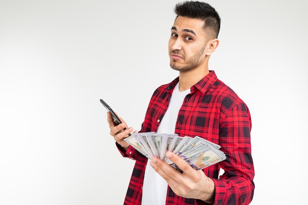 Guy in una camicia a quadri riferisce vincendo i soldi per telefono su uno sfondo bianco con spazio di copia