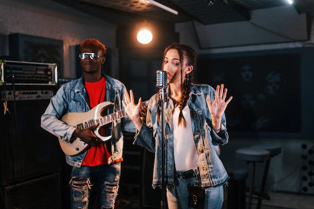 Guy plays guitar girl sings African american man with white girl rehearsing in the studio together