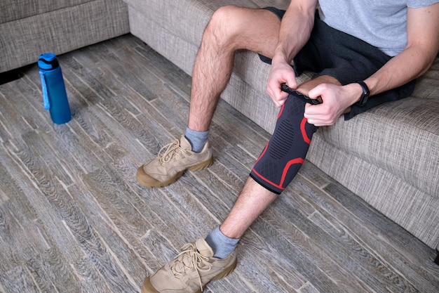 The guy puts a compression bandage on the injured knee\
preparing for sports activities the sore spot is highlighted in\
red