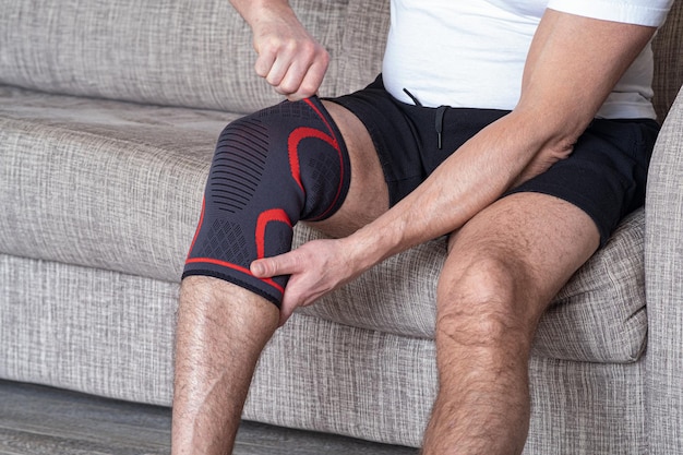 Photo the guy puts a compression bandage on the injured knee preparing for sports activities the sore spot is highlighted in red