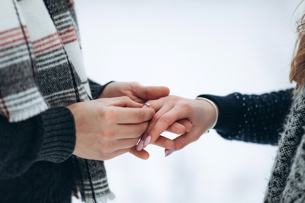 The guy puts the engagement ring on the hand of his girlfriend by making an offer to get married