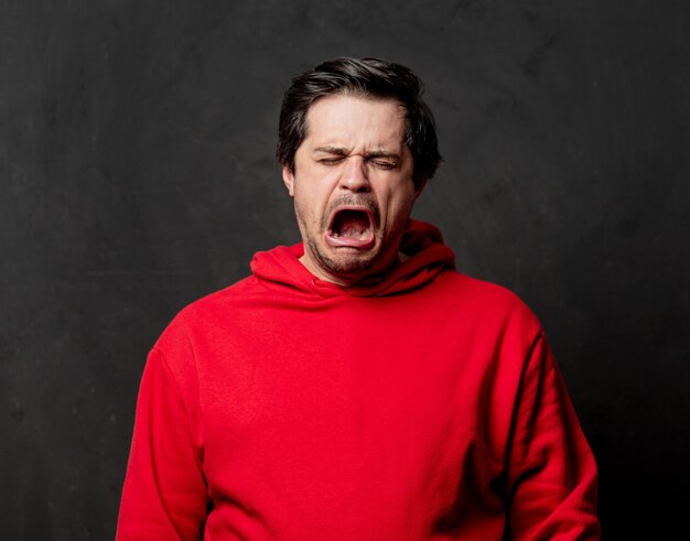 Photo guy in red sweatshirt on dark wall