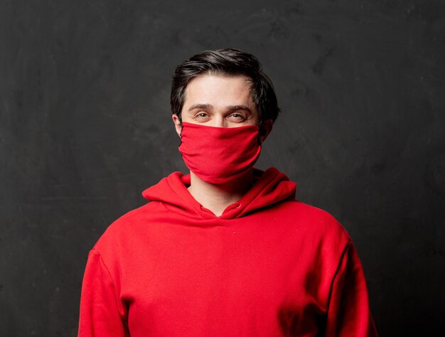 Guy in red sweatshirt and face mask on dark wall