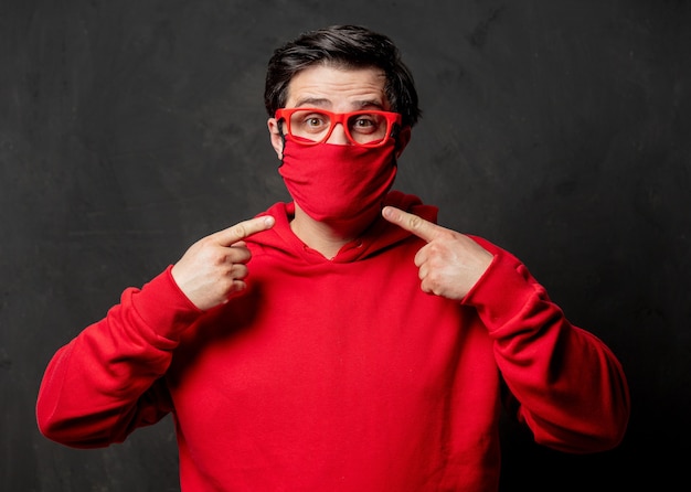 Guy in red sweatshirt and face mask on dark wall