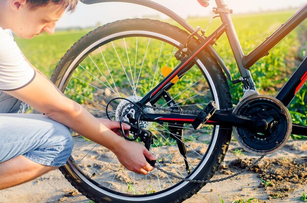 The guy repairs the bicycle chain repair cyclist unratitude on the road travel close-up