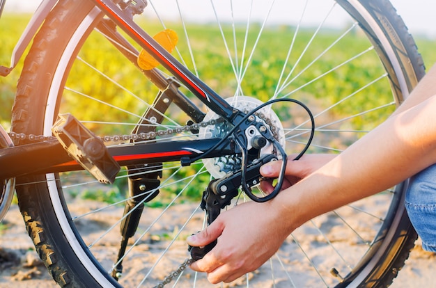 その男は自転車を修理する。チェーン修理。サイクリスト。道路上の狂気、旅行、クローズアップ。