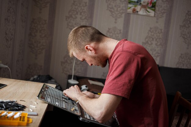 Guy repairs laptop at home