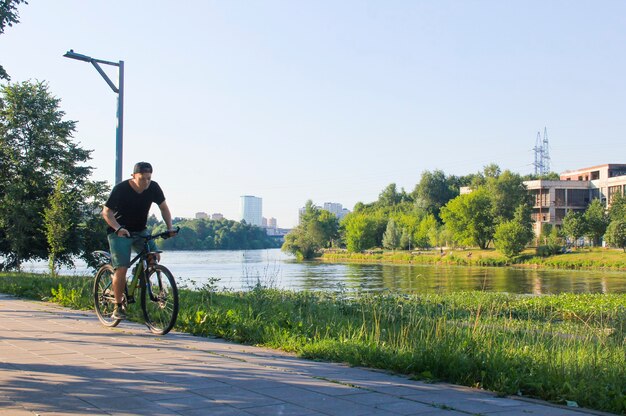 男が公園で自転車に乗る。晴れた日の自転車に乗っている間の若いフィットの男。ぼやけた焦点