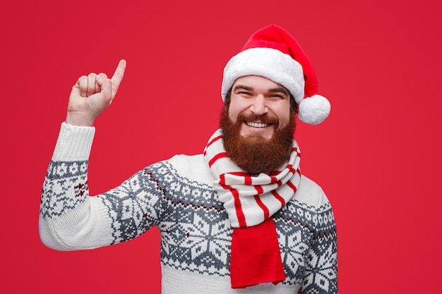 Photo guy in santa hat smiling and pointing up