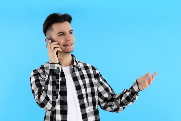 Ragazzo in camicia con telefono su sfondo blu