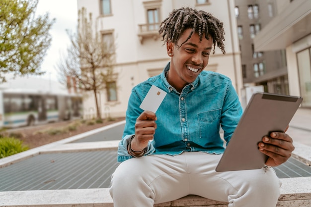 Photo guy showing card on tablet sitting on street