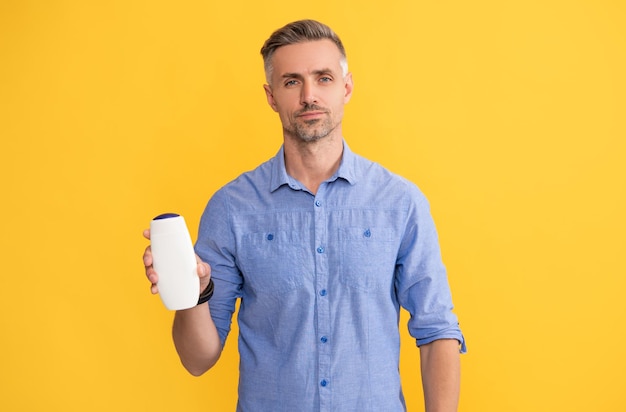 Guy showing hair conditioner on yellow background advertisement