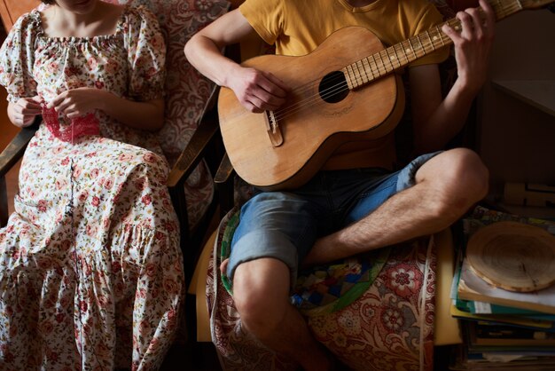 Photo the guy sitting playing guitar with a girl who knits the product