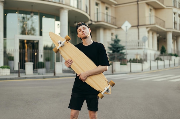Guy skateboarder posing with a longboard in his hands
