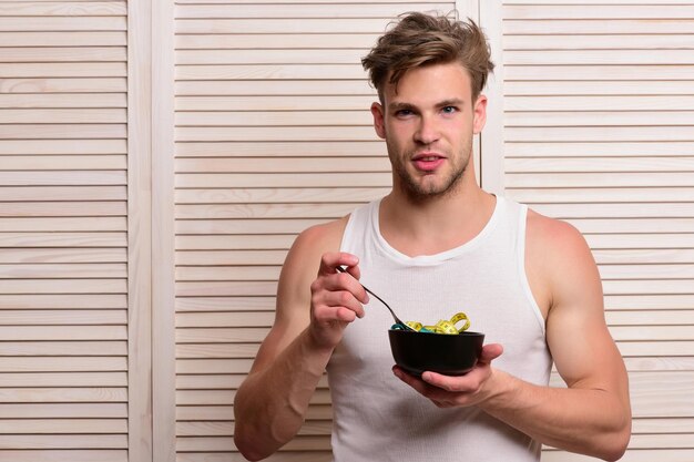 Guy in sleeveless shirt holds bowl with measuring tape inside