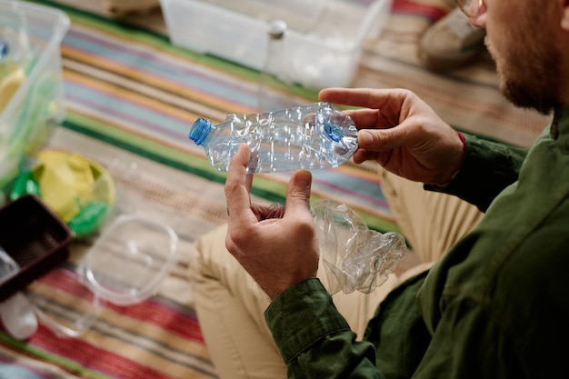 Foto un tizio che rompe bottiglie di plastica vuote.