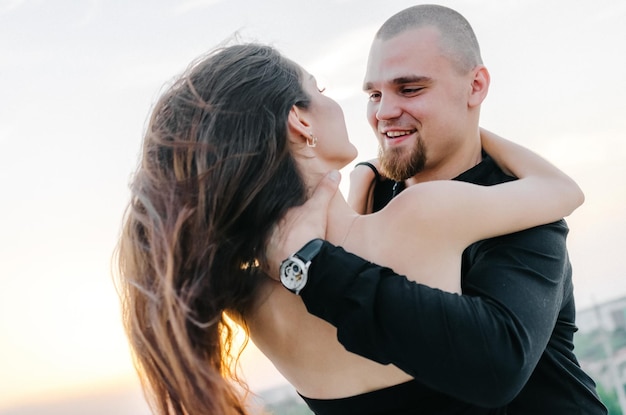 the guy smiles and hugs the girl by the neck