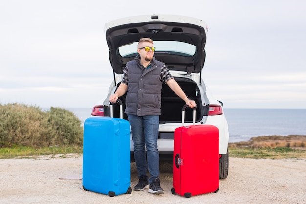 Guy standing in back of car smiling and getting ready to go. Young laughing man standing near open