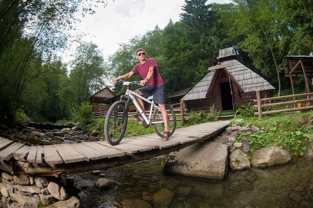 Guy standing on the bridge over the river with bike